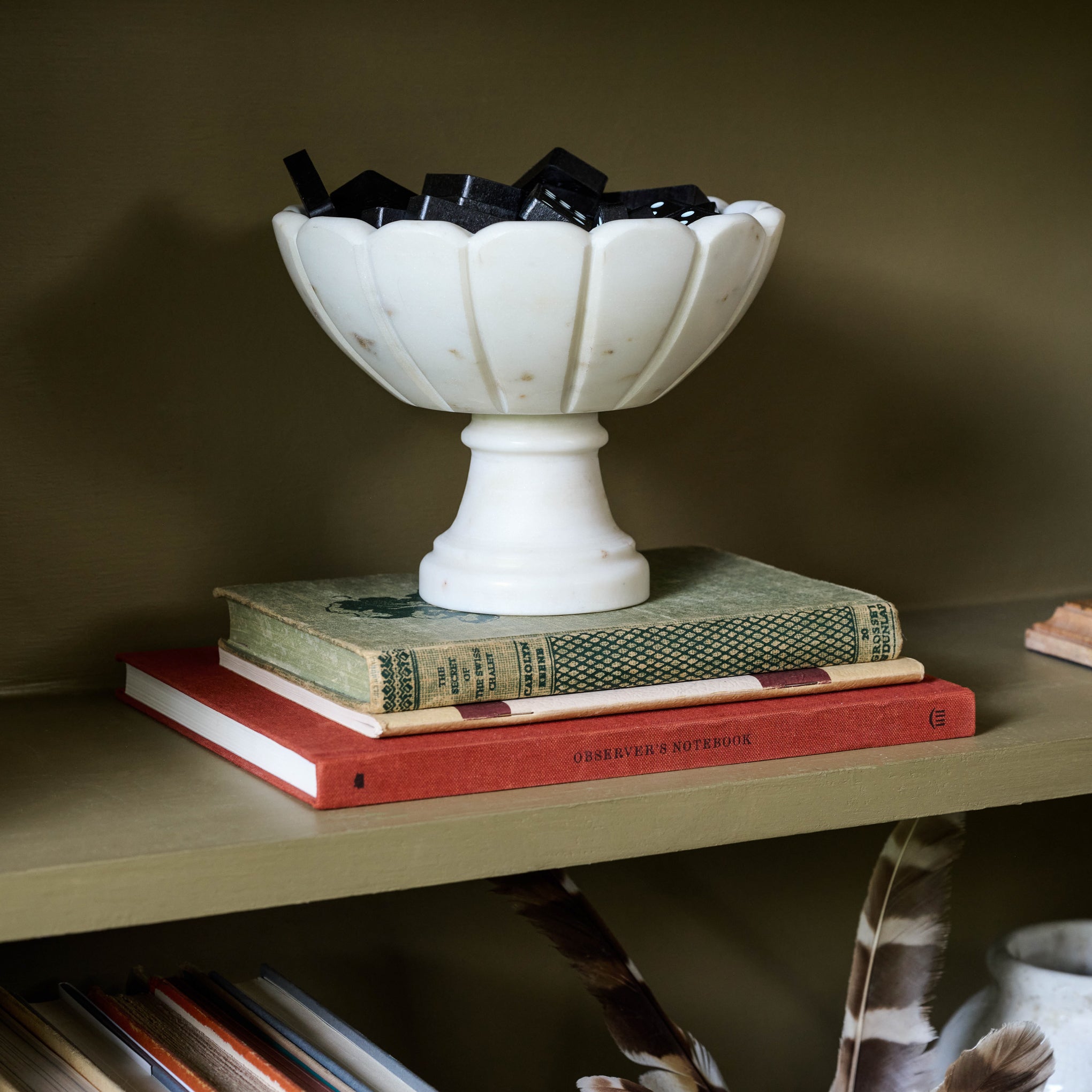 Marble Scalloped Accent Bowl containing dominoes on a bookshelf $50.00