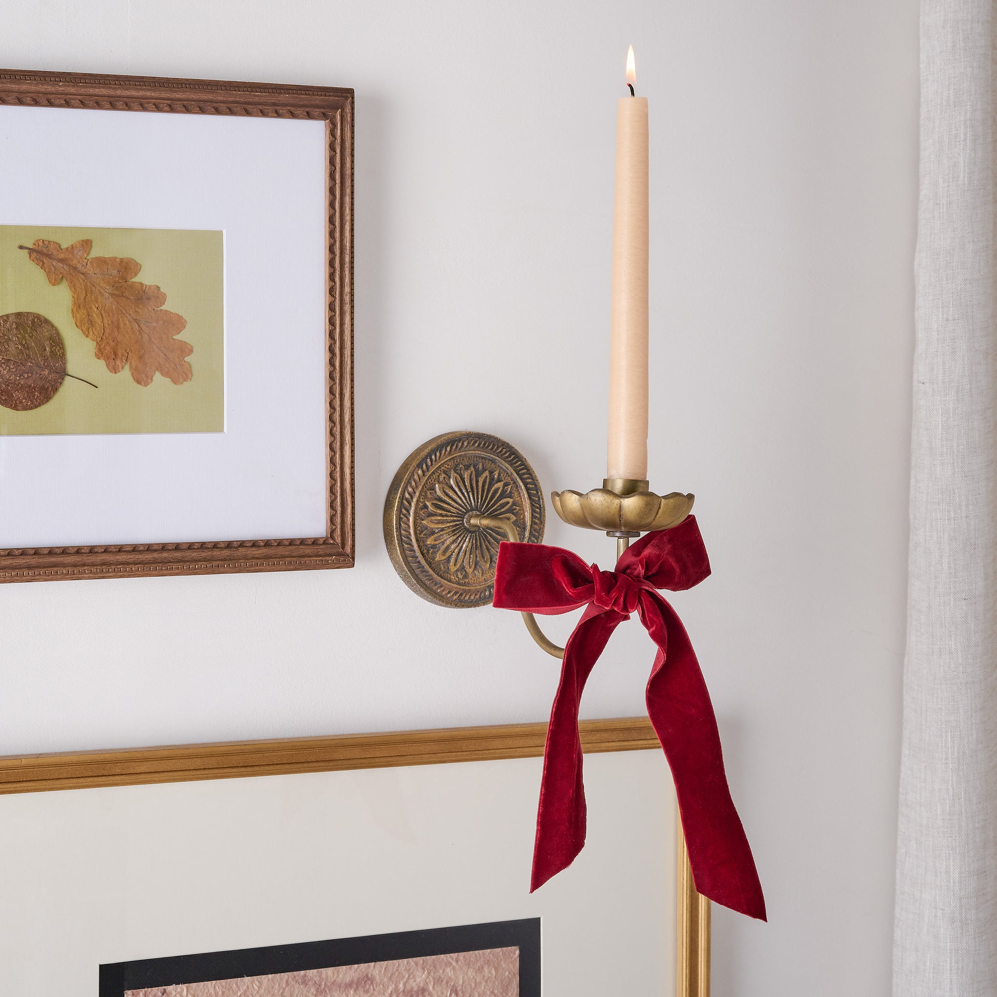 Anna Antiqued Brass Wall Sconce with ribbon attached and burning candle