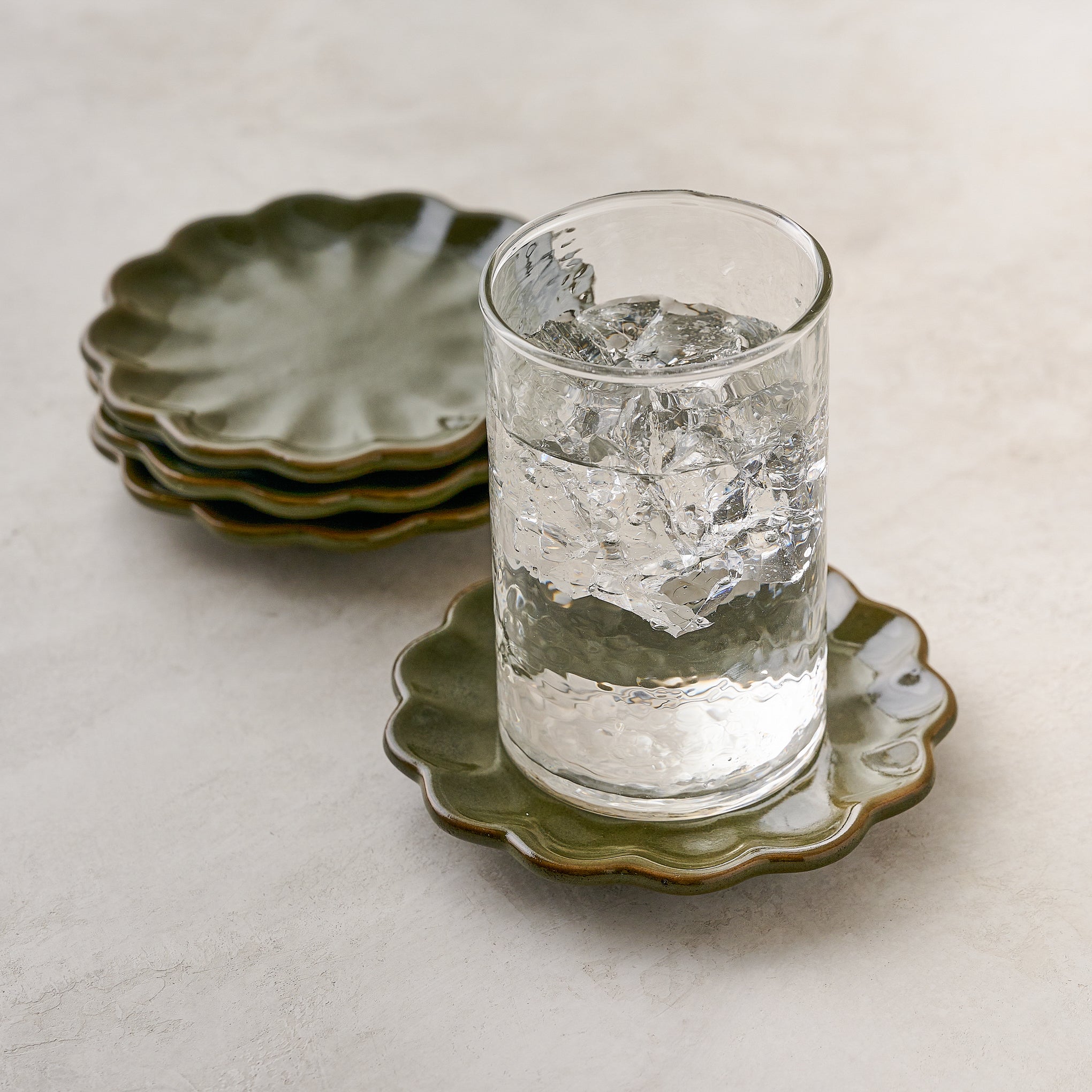 Sage Scalloped Edge Coaster Set of Four shown with glass of water $28.00