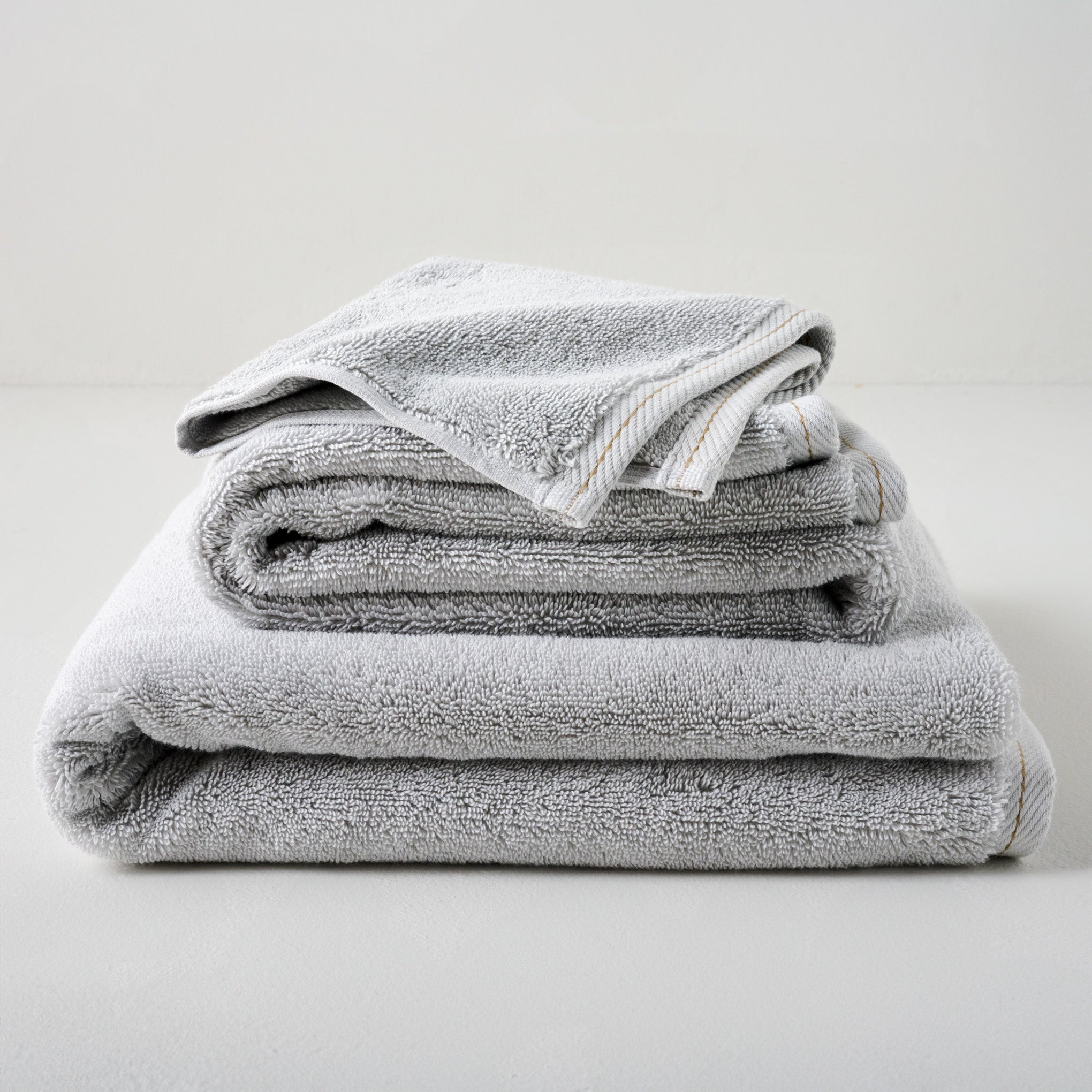 Magnolia Grey Plush Stitched Edge Towels shown stacked Items range from $14.00 to $42.00