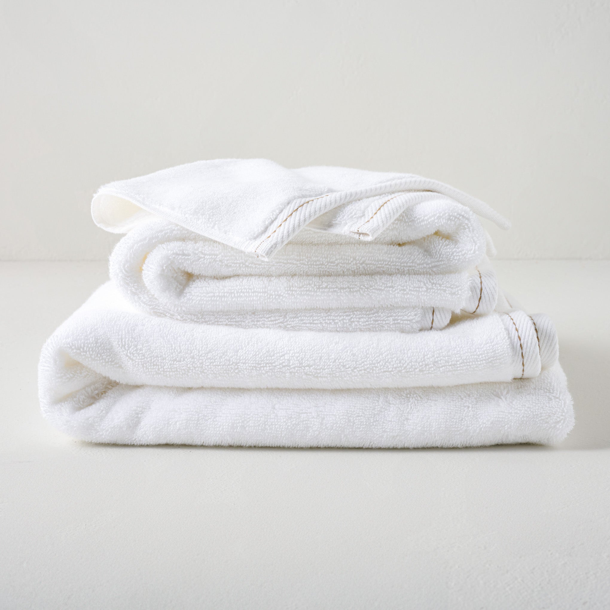 Magnolia White Plush Stitched Edge Towels shown stacked Items range from $14.00 to $42.00