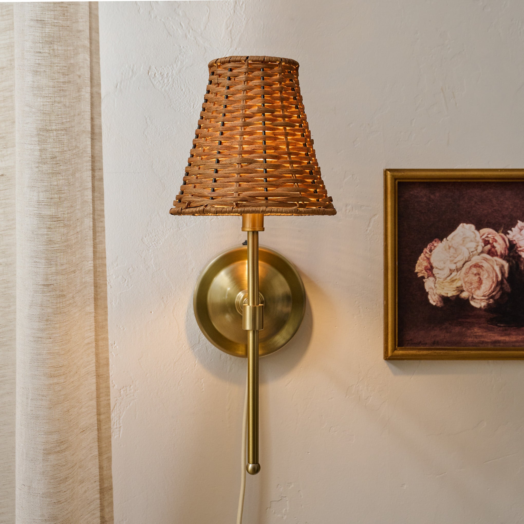 Rattan Plug-In Wall Sconce shown on wall with wall art $118.00