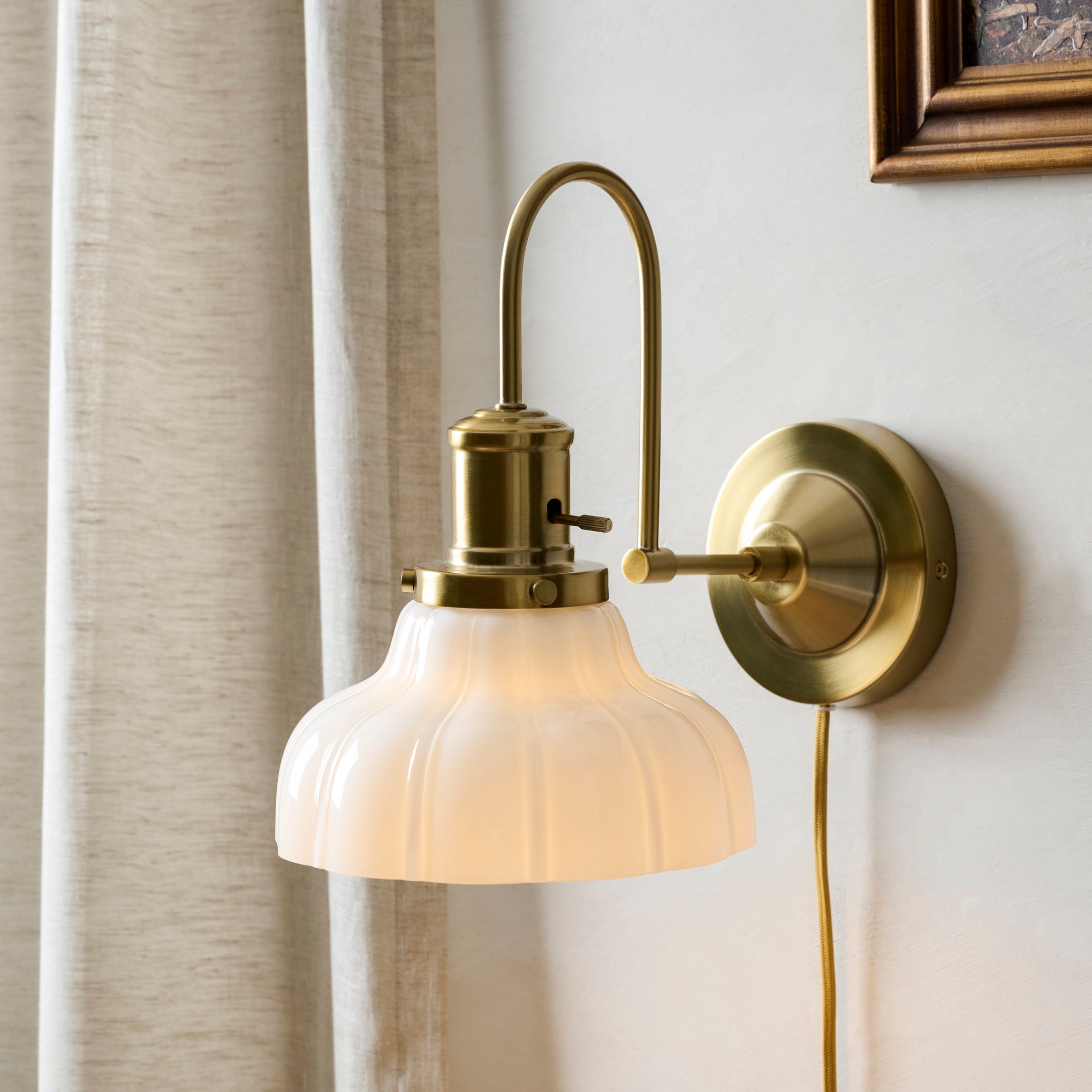Polly Milk Glass Plug-in Sconce shown on wall $118.00