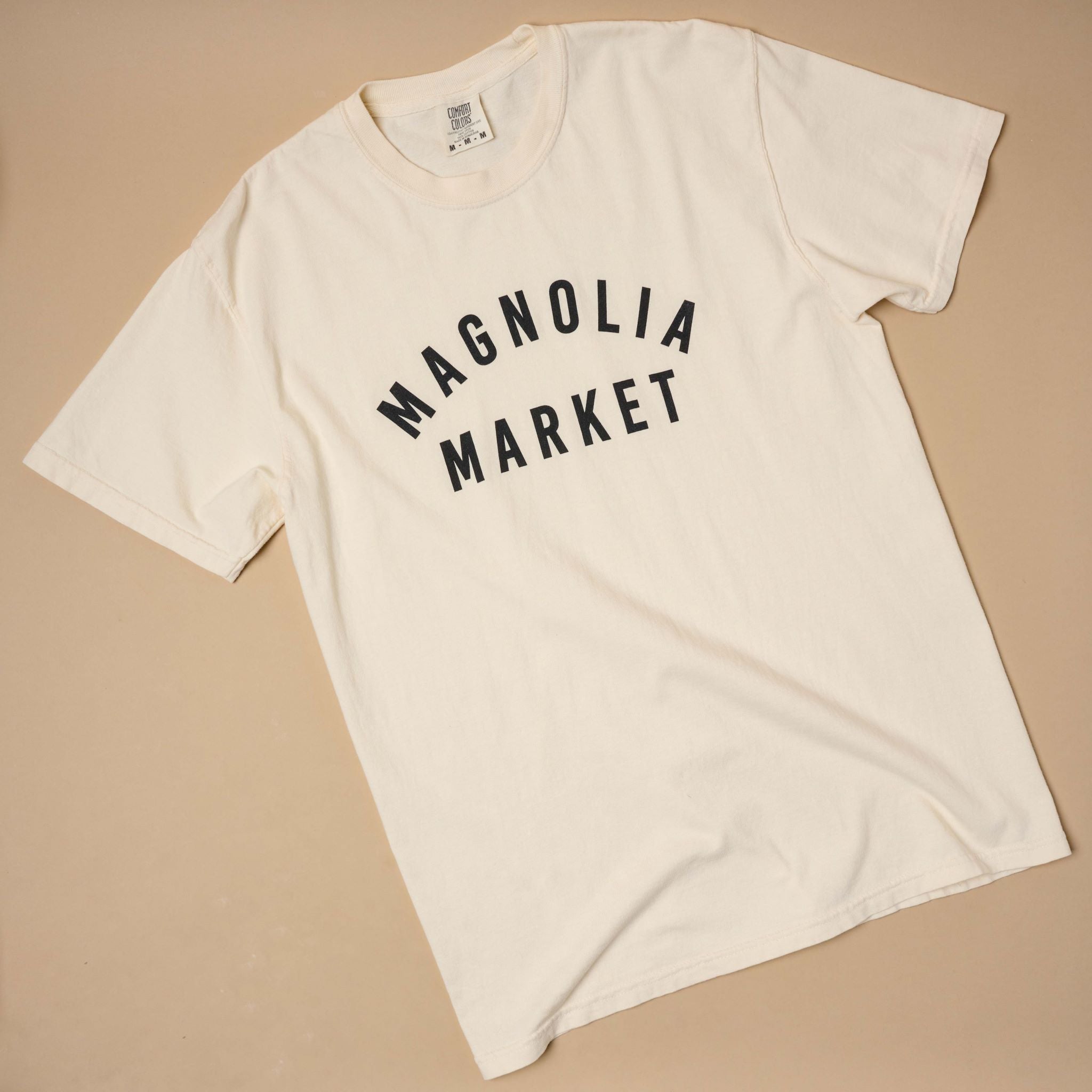 Top view of Magnolia market ivory shirt that reads Magnolia Market in plain black text.