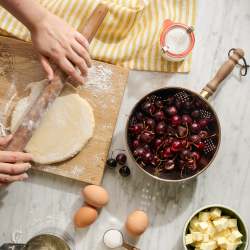 Copper Colander with Walnut Handle containing cherries on a countertop