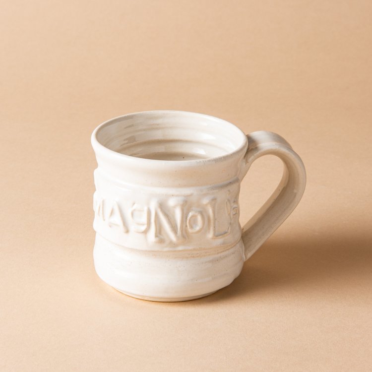 white handthrown ceramic mug with original Magnolia logo embossed on side